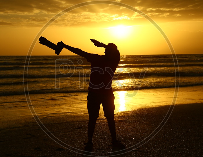 Silhouette Of a Photographer  With DSLR At a Beach With Sunset Golden Sky In Goa