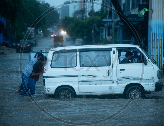 Men Pulling a Van  On Flooded Road At Hi-tech City