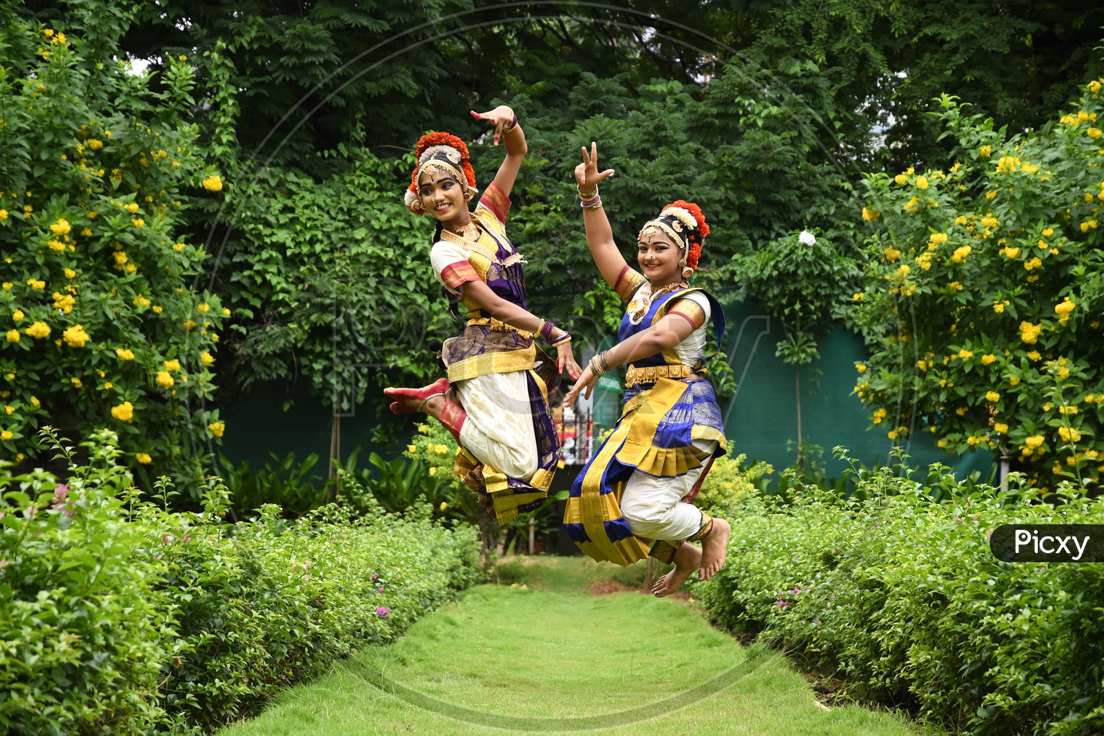 Indian Bharatanatyam Dancers jumping in the Lawn