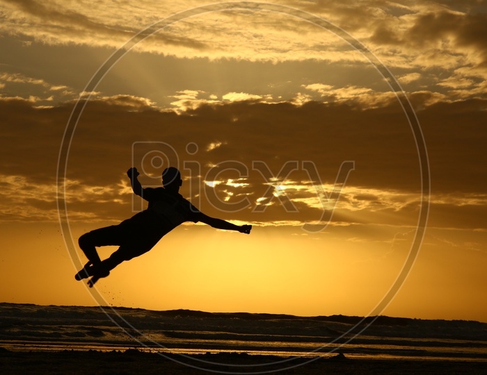 Silhouette Of a Man Doing Gymnastics In a Beach With Sunset Golden Sky In Background  At Goa