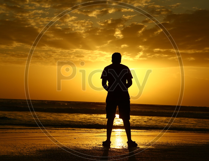 Silhouette Of a Man Standing In a Beach Over Golden Sunset Sky In a Beach At Goa