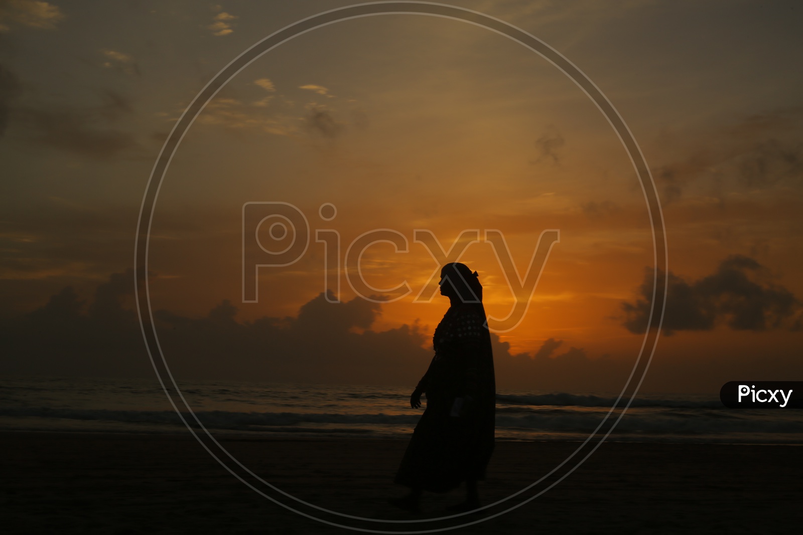 Silhouette Of a Woman Standing In a beach Alone With Sunset Sky In Background
