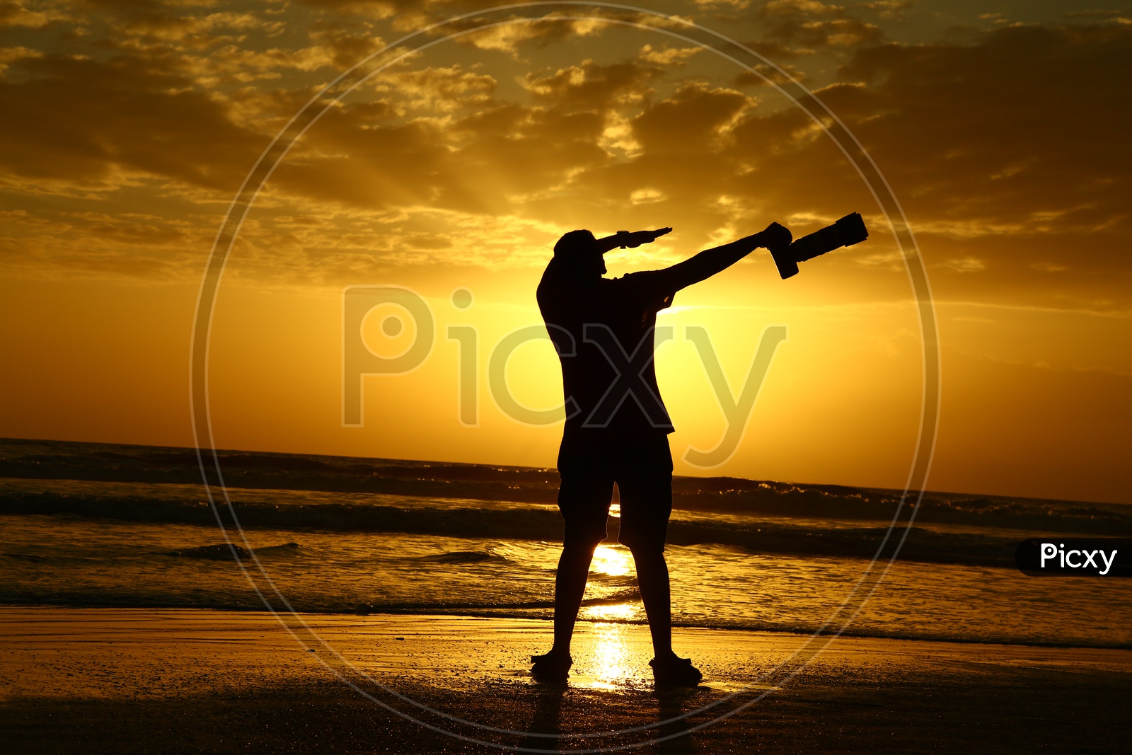 Silhouette Of a Photographer Jumping In Joy With DSLR At a Beach With Sunset Golden Sky In Goa