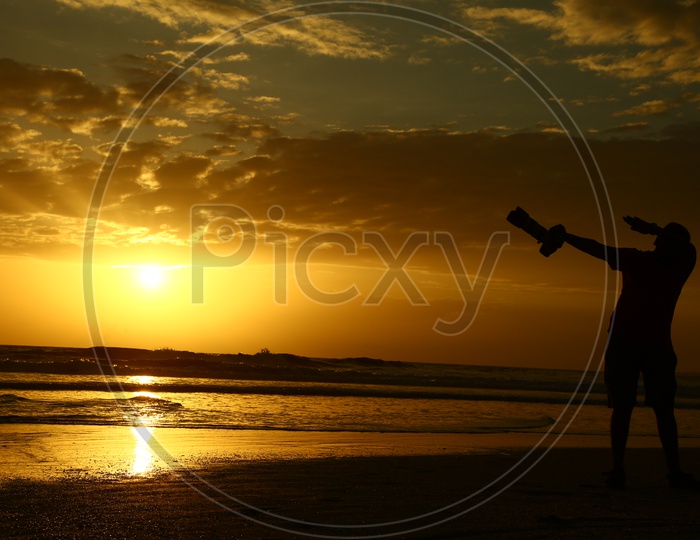 Silhouette Of a Photographer  With DSLR At a Beach With Sunset Golden Sky In Goa