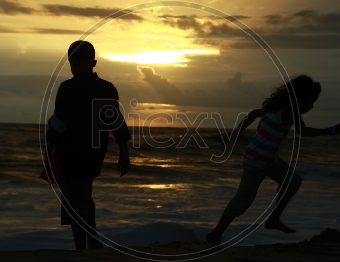Silhouette Of Father And Daughter In a Beach With Sunset Sky In background
