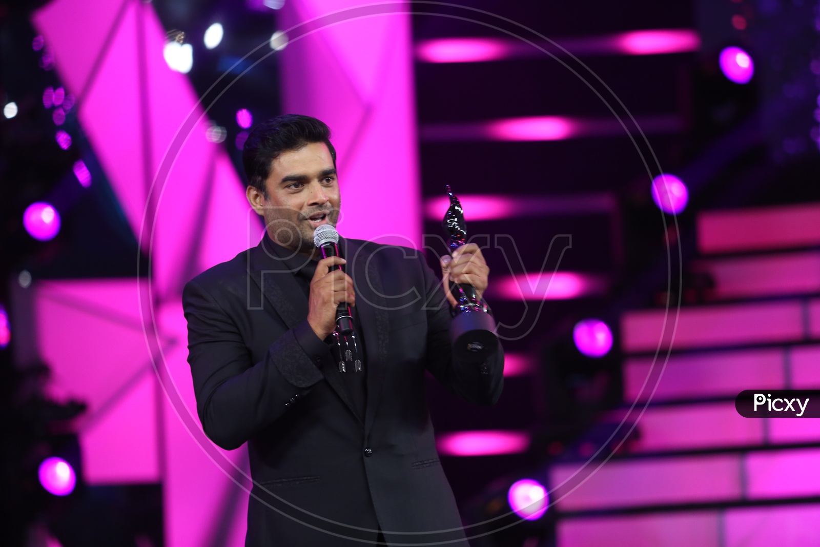 Actor Madhavan showing the Filmfare award on the stage