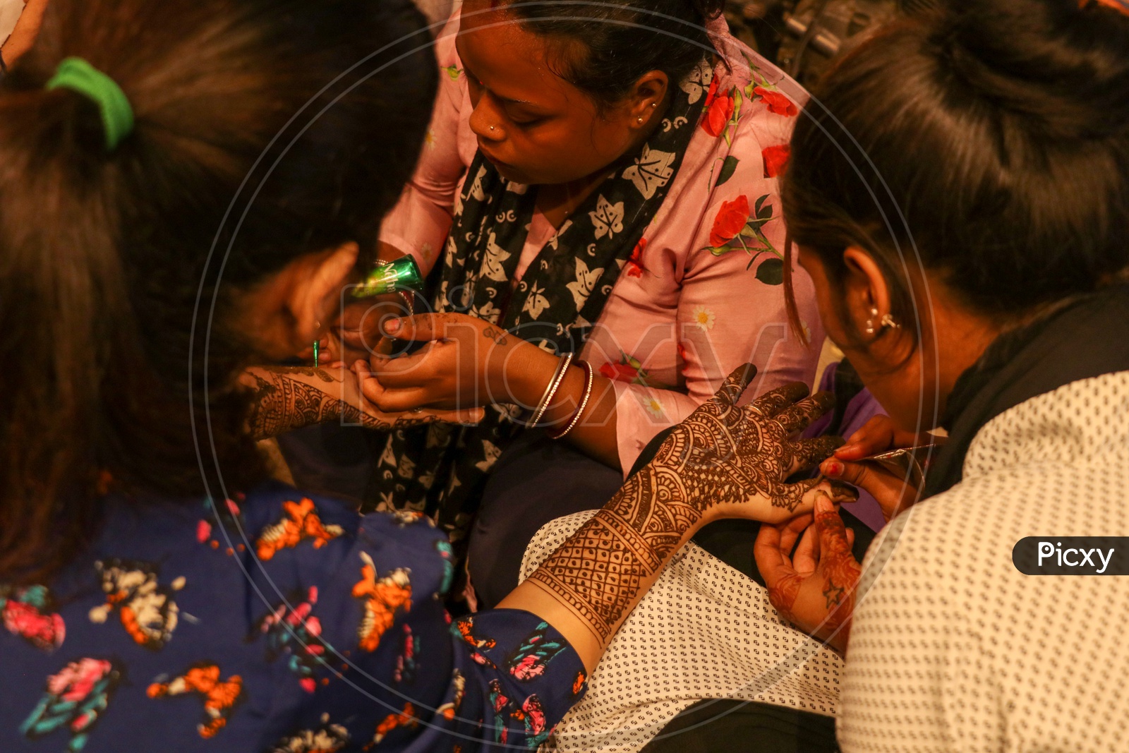 Mehandi artists keeping design on a woman's hand