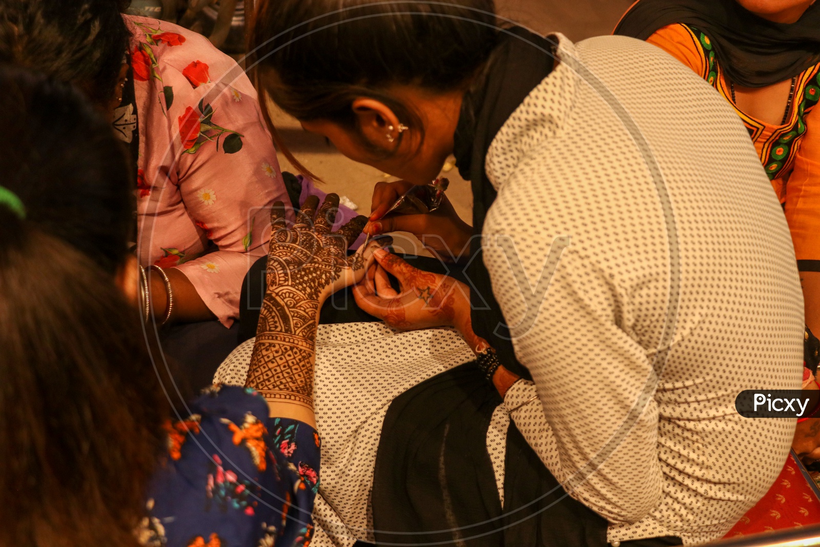 Mehandi artist keeping design on a woman's hand