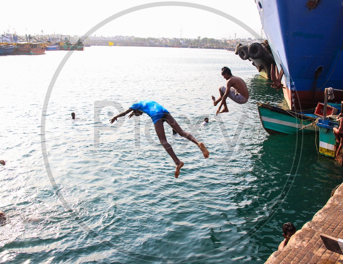 Children jumping off boats into the sea at the port of Vizag.