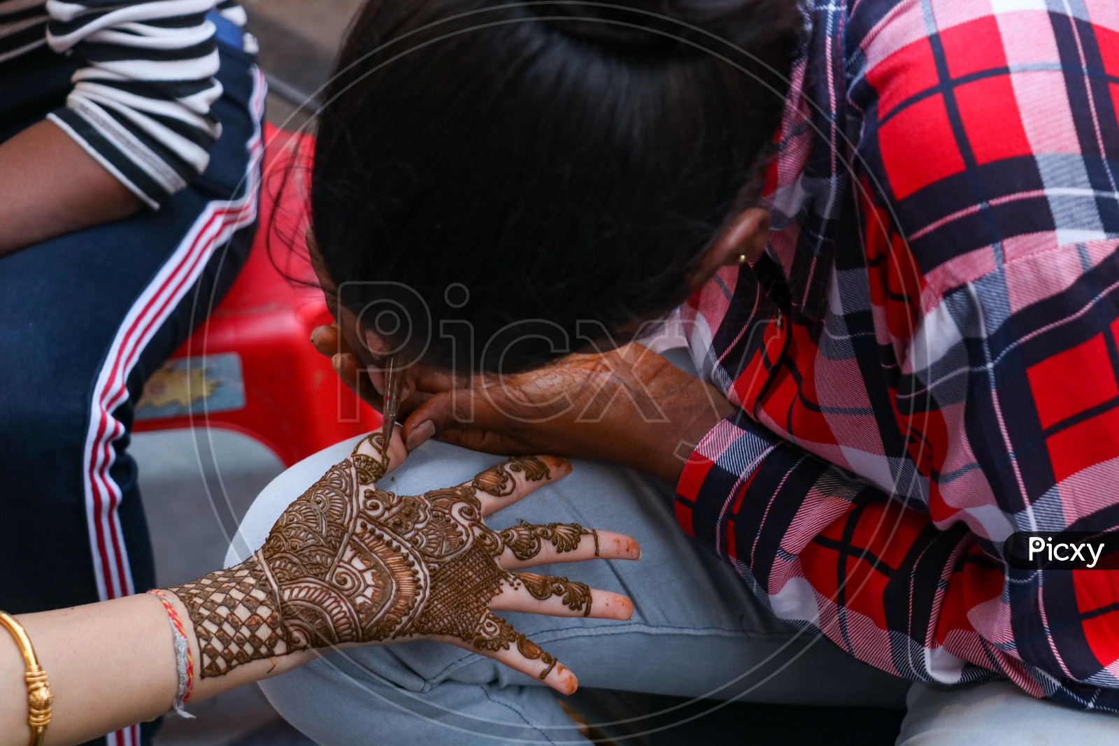 Mehandi artist keeping design on a woman's hand