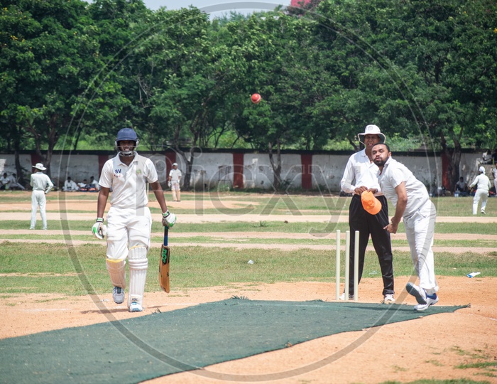 Cricket pitch with batsmem, bowler, empire in action