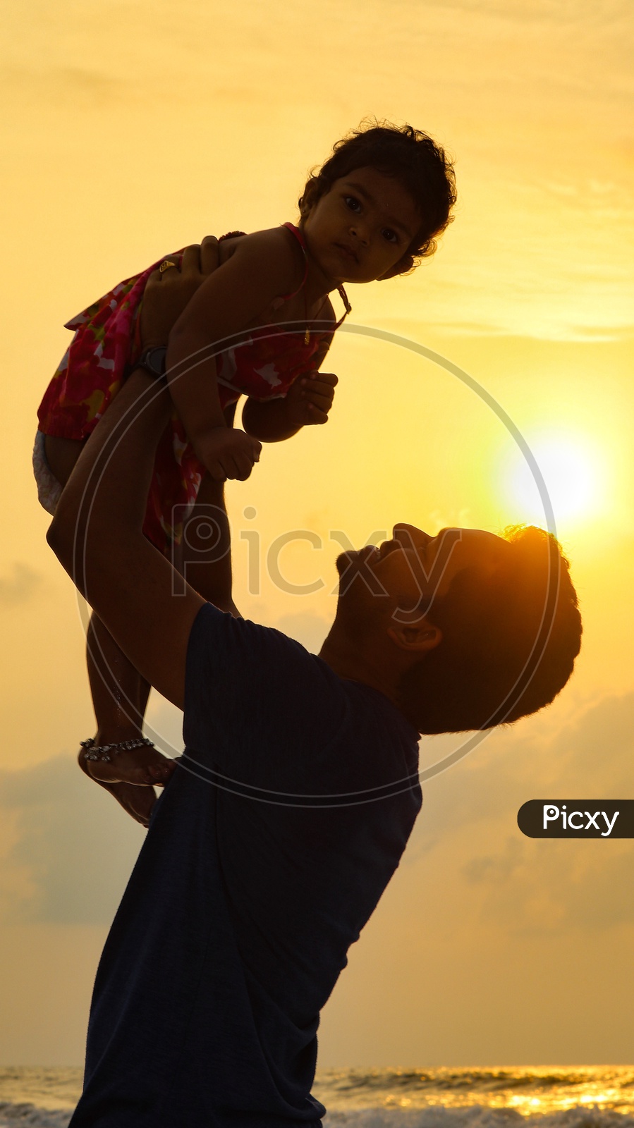 A father playing with his daughter at beach sunrise