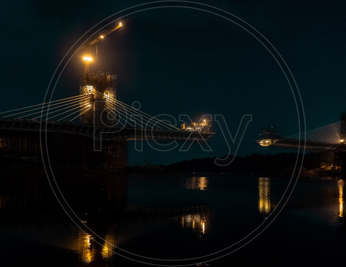 Durgamma Cheruvu cable bridge at night with water reflection.