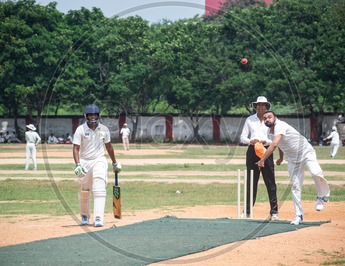 Cricket pitch with batsmem, bowler, empire in action