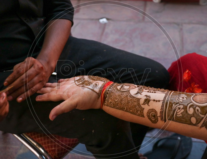 Indian Woman Putting On Mehandhi Designs To Their Hands At a Mall In Festival Season
