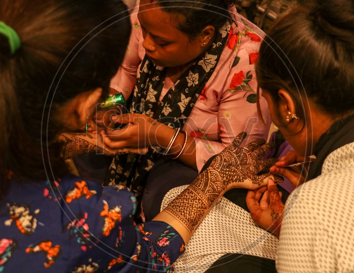 Mehandi artists keeping design on a woman's hand