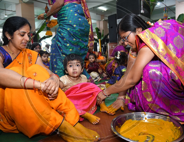 An Indian Hindu woman applying turmeric paste onto Girl feet prior to performing prayers to the Hindu Goddess Kanaka Durga