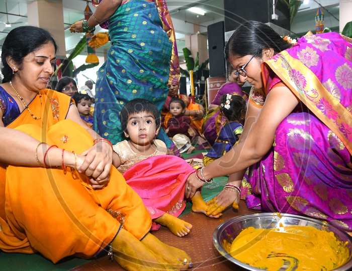 An Indian Hindu woman applying turmeric paste onto Girls feet prior to performing prayers to the Hindu Goddess Kanaka Durga