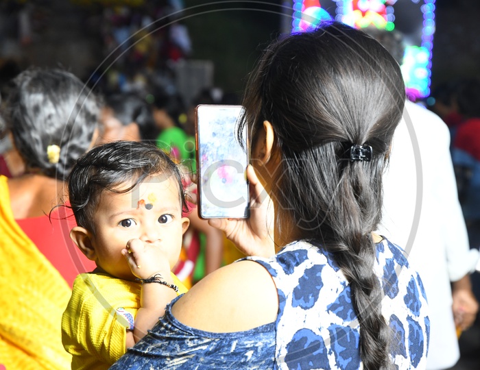 A Mother using Smartphone For Recording by Carrying Her Child