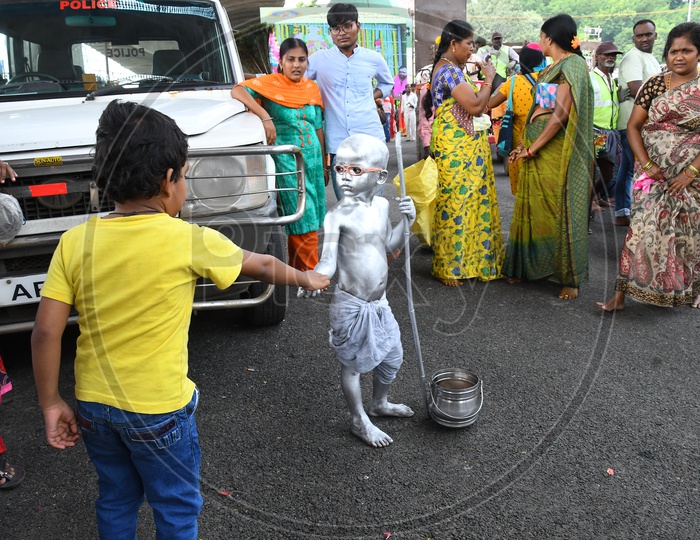 Indian Boy or Street Artist  As Mahatma Gandhi Getup And Painted in Silver Begging on Streets of Vijayawada During  Durga Navratri Festival