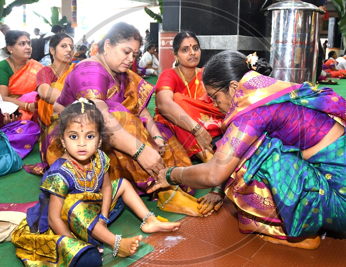 An Indian Hindu woman applying turmeric paste onto Girls feet prior to performing prayers to the Hindu Goddess Kanaka Durga