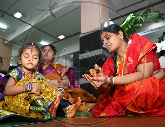 Woman Devotee Applying Turmeric Paste To Girl Child Legs  As a Tradition During Dussera Durga Navratri