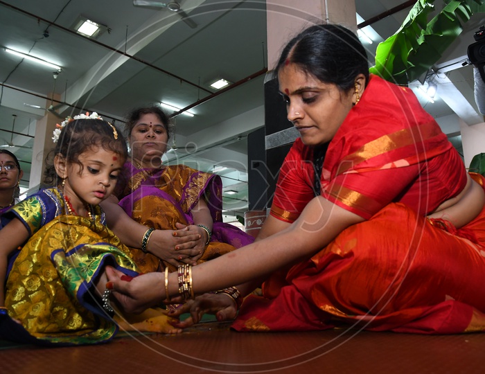 Woman Devotee Applying Turmeric Paste To Girl Child Legs  As a Tradition During Dussera Durga Navratri