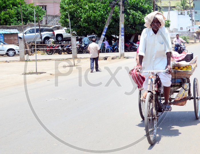 Indian Old Man selling fruits on a trolley Rickshaw