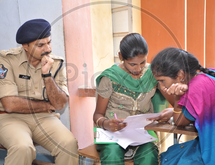 AP Police Man watching over the student substituting exam writing for a blind girl