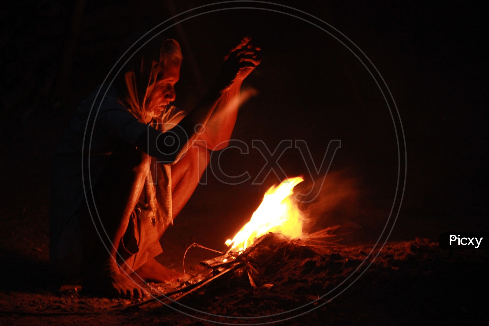 Indian Old Man at fireplace during winters