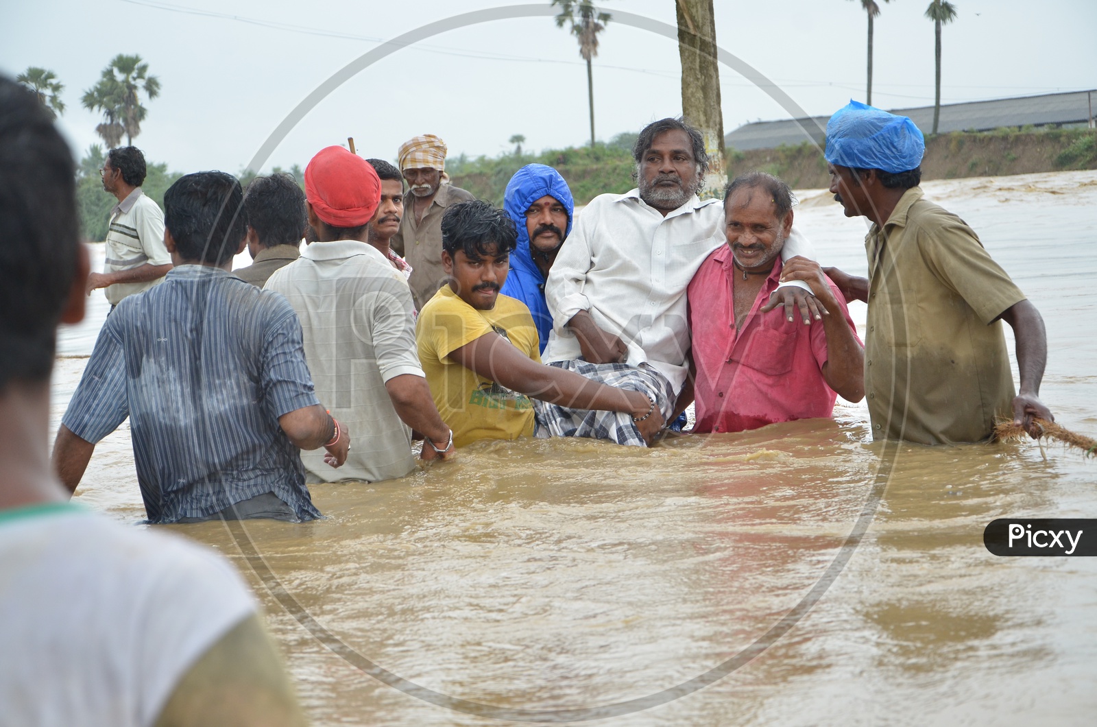 Image Of Indian Men Helping Old Man Evacuate House During Floods