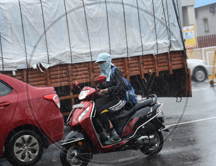 A Two Wheeler Commuter without Helmet driving in Rain