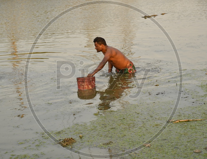 Indian man collecting water from a pond