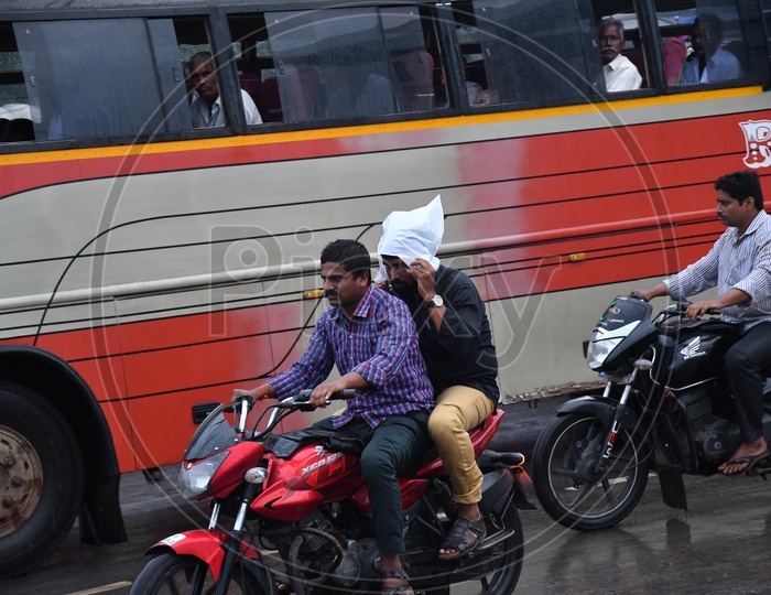 Two Wheeler Commuters Commuting in Rain without Helmets