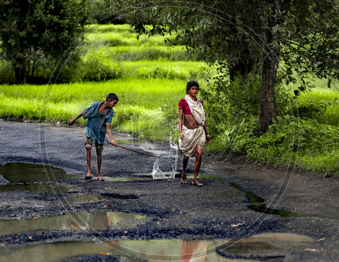 A Boy Splashing WaterPits on Roads  in Rural Vilages