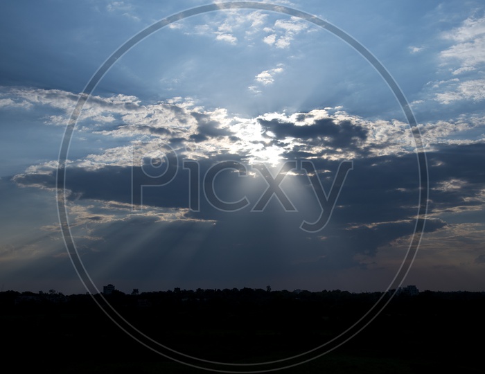 Sunset Sky With Dark Clouds In Sky With Sun Rays Forming a Background