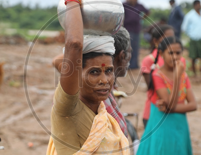 Indian Old Woman carrying a steel can on her head