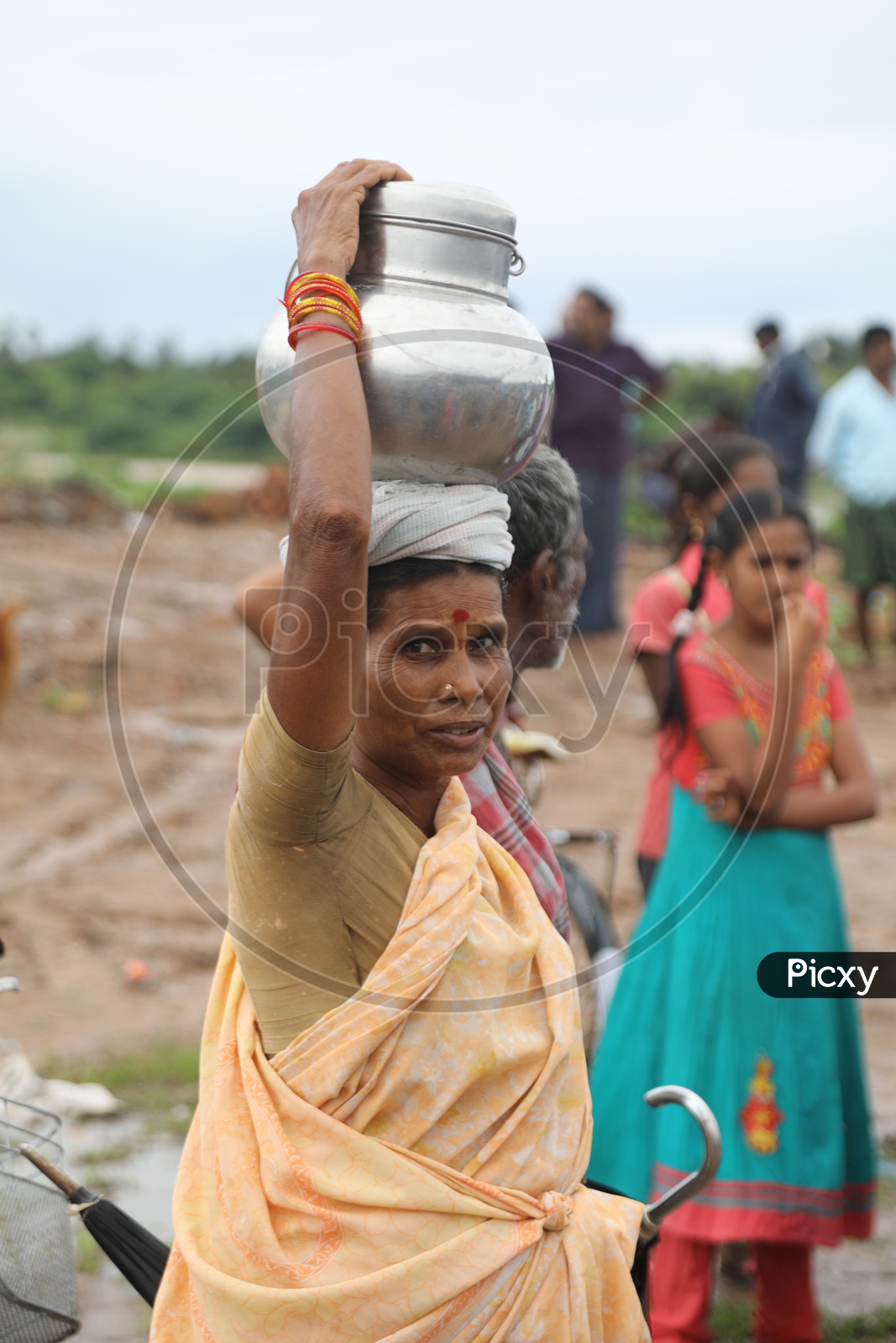 Indian Old Woman carrying a steel can on her head