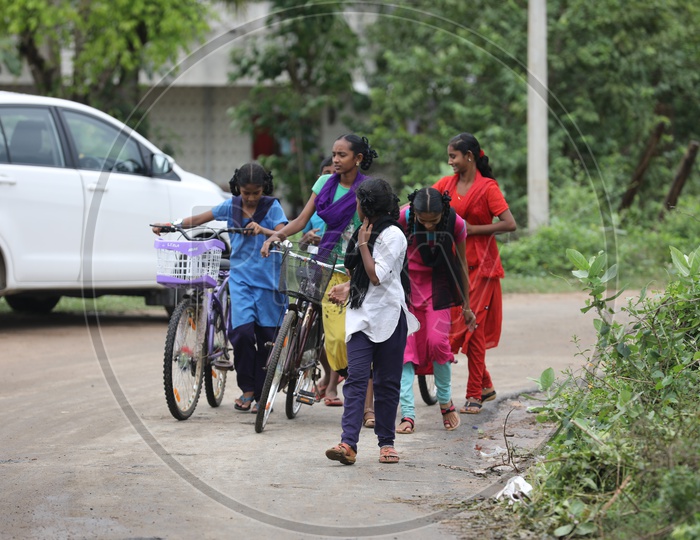 Group of Indian Rural Girls walking with their bicycles