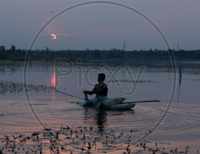 Fisherman Fishing in a Lake With Sunset Sky In Background