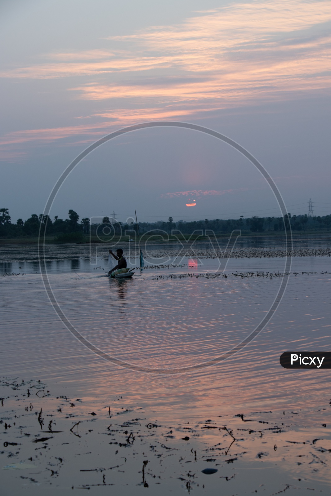 Fisherman Fishing in a Lake With Sunset Sky In Background
