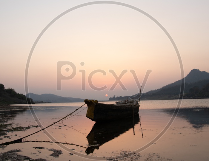 Lone Fishing Boat Anchored In Godavari river With Sunset Background