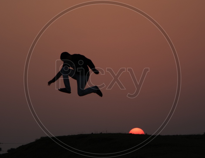 Silhouette of a Man Jumping in Joy With Sunset Sun In Background