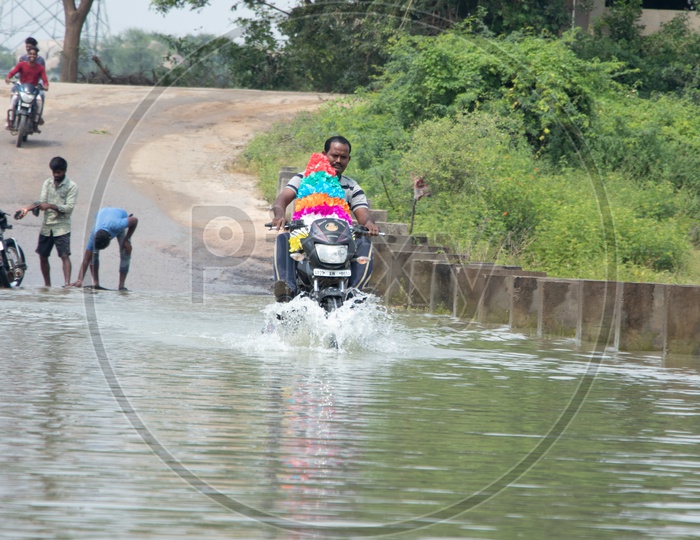 Man Carrying Bhathukamma On Bike And Crossing Flooded  Bridge  At Rural Village Of Telangana