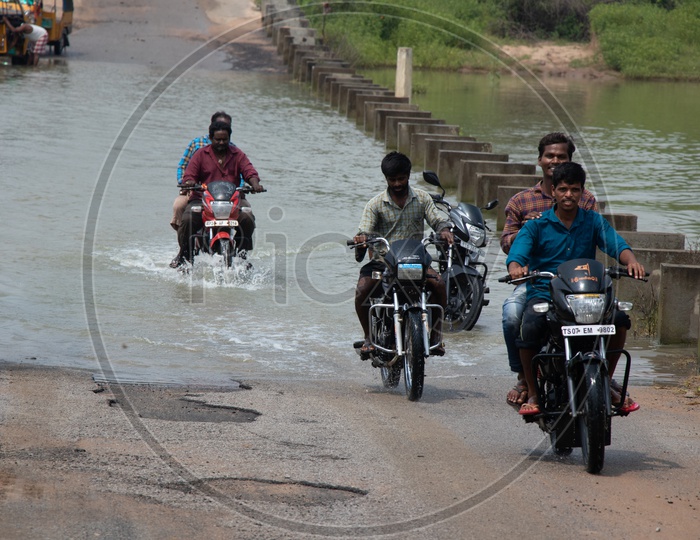 Bikers Passing Through A Flooded Bridge  In Rural Villages Of Telangana