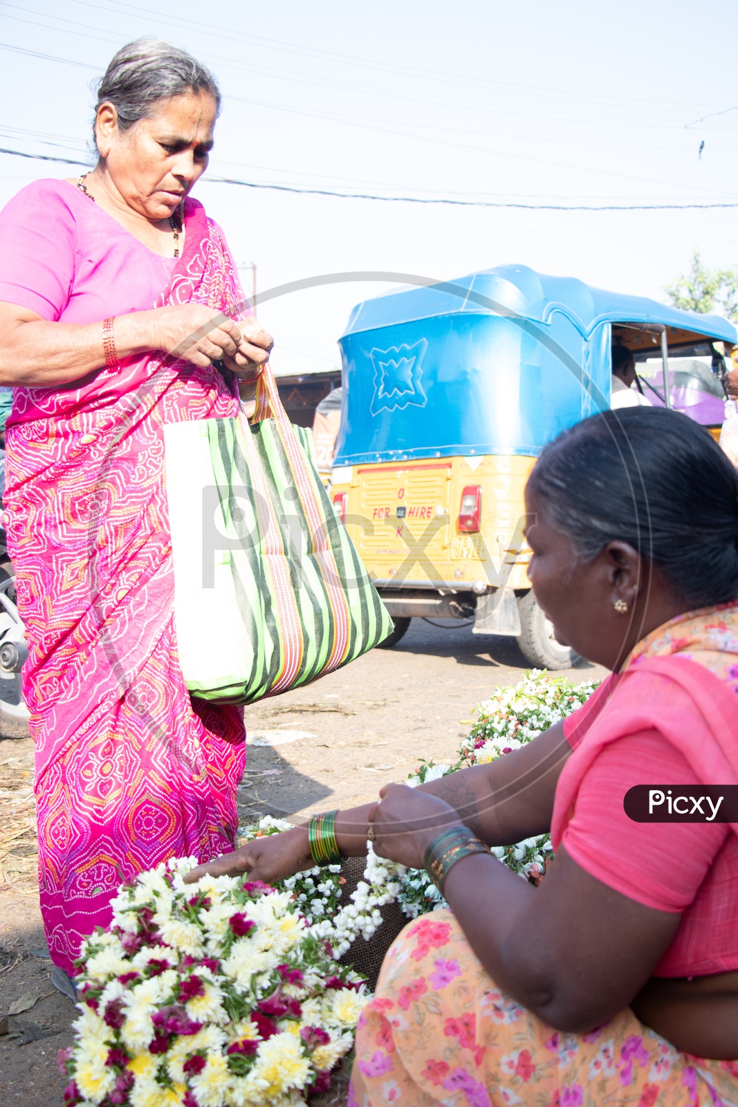 A Woman Buying Flower Garlands From a Woman Vendor