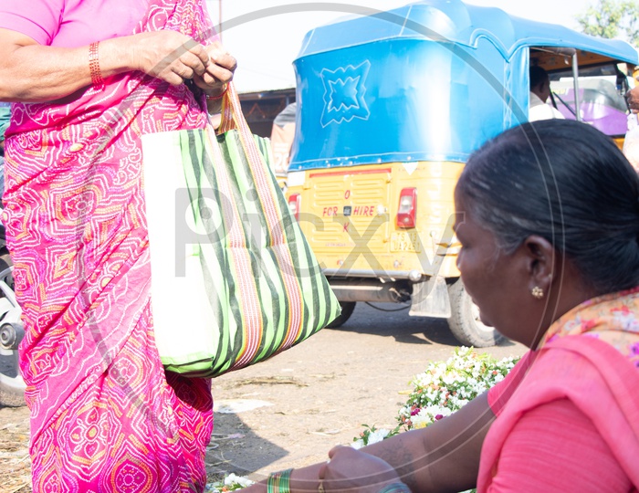 A Woman Buying Flower Garlands From a Woman Vendor