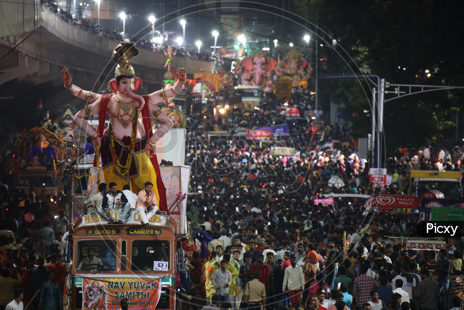 Image of Ganesh Idols In Trucks And Crowd Of Devotees At Tank Bund For