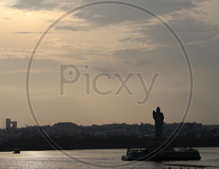 Silhouette Of  Buddha Statue In Hussain Sagar Lake With Telangana Tourism Boat  and Sunset Sky In Background
