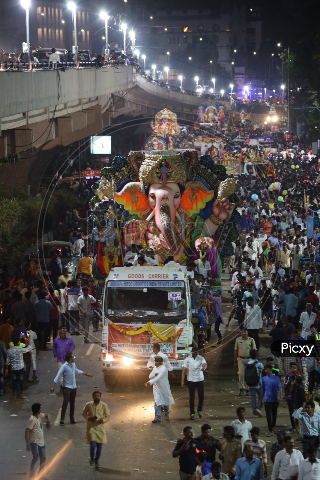 Image of Ganesh Idols In Trucks And Crowd Of Devotees At Tank Bund For